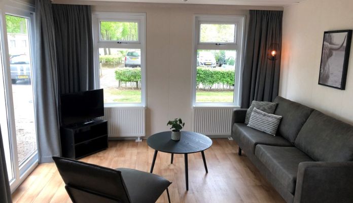 Large living room with black and grey modern furniture with a sofa, TV and armchair in Comfort mobile-home