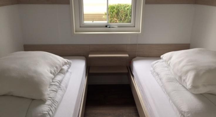 Bedroom with 2 separate simple beds with pillows and duvets